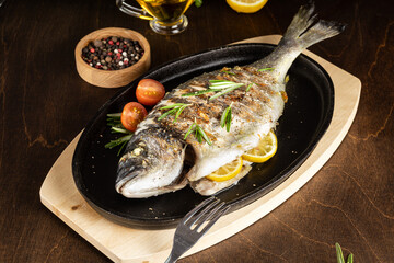 roasted dorado fish with lemon on dark wooden background. Copy space.