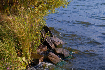 lake shore at sunset with rocks and waves.