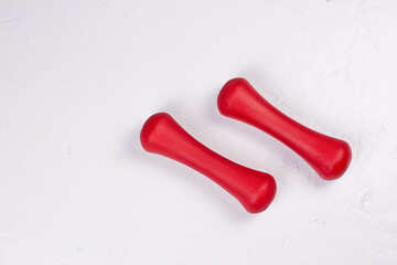 Two red dumbbells on white background flat lay image. Fitness and activity minimal concept.