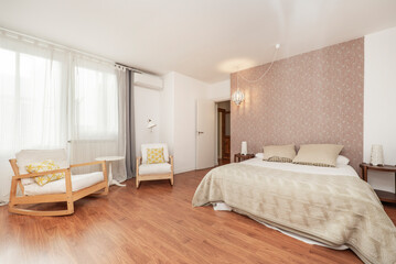Bedroom with a double bed, wooden rocking chairs, light wooden floors and a large window with curtains
