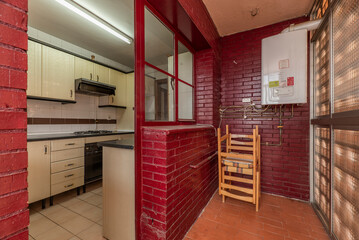 Drying terrace of a house with bricks and window frames painted red and access to a kitchen