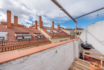 Terrace of a house with charcoal barbecue and views of the roofs with skylights and chimneys of the...