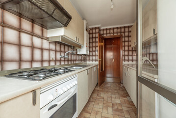Antique kitchen with gas burners, cream Formica cabinets and countertops, and kitsch tile