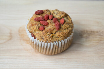 Tasty Sugar Almond Flour Muffin with Goji Berries on a Wooden Board.