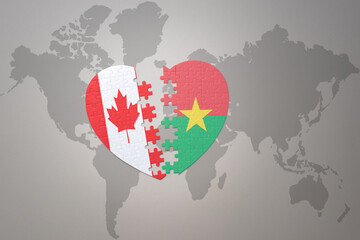 puzzle heart with the national flag of canada and burkina faso on a world map background.Concept.