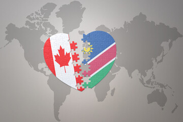 puzzle heart with the national flag of canada and namibia on a world map background.Concept.
