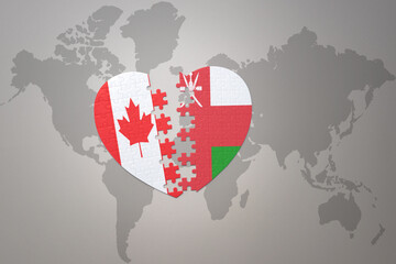 puzzle heart with the national flag of canada and oman on a world map background.Concept.