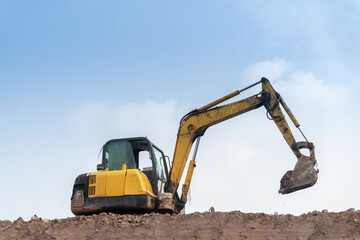 excavator digging and loading dirt at the construction site with empty sky for copy space.