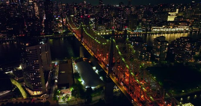 Tremendous Queensboro Bridge in orange and green lights. Lively traffic in neversleeping New York. Cityscape with billions of lights at backdrop.