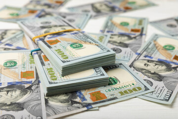 Money, US hundred dollar bills background on white wooden background. Money is scattered on the table. Finance and economics concepts.Money accumulation concept.Currency saving.Investment.Copy space.