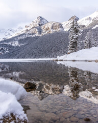 Lake Louise, Alberta, Canada - Incredible mountain scenery in winter time with reflection of trees in water below. 