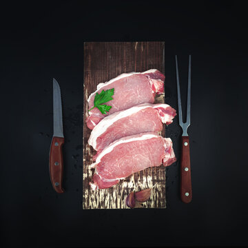 Raw veal meat fillet on kitchen cutting board with ingredients for cooking, knife and meat fork on dark background