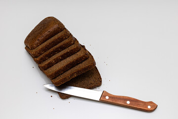 a cut piece of black bread next to which lies a knife