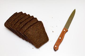 a cut piece of black bread next to which lies a knife