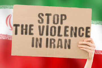 The phrase " Stop the violence in Iran " is on a banner in men's hands with a blurred Iranian flag in the background. Sad. Rights. Security. Social. Stress. Combat. Hate. Cruelty. Furious