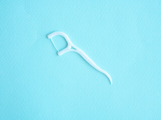 Dental floss with white plastic toothpick on blue with space for text. Dental concept