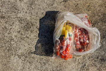 Barbecue skewers in plastic bags are placed on the ground in the sun to help relieve the coldness...