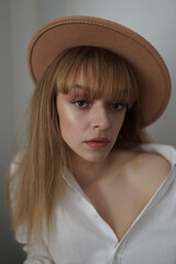 In the photo, a beautiful girl in a white shirt, long hair and a gallows hat is being photographed