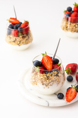 Homemade granola with almonds in a glass with yogurt, fresh strawberries and blueberries, delicious healthy breakfast