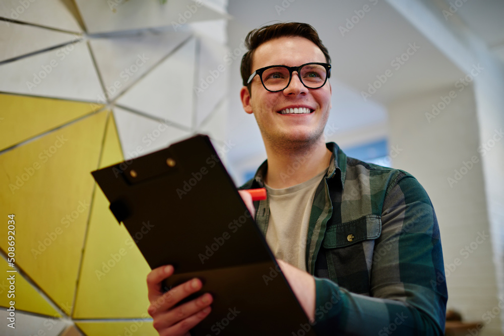 Poster young smiling male student writing notes in notebook while learning. man freelancer work on notebook