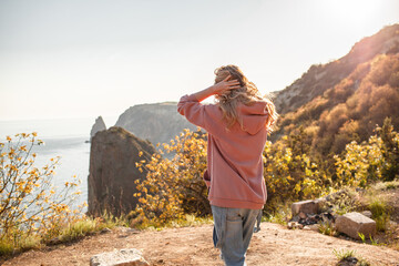 Beautiful woman dressed jeans and hoody walking in the nature against background sea and nountains