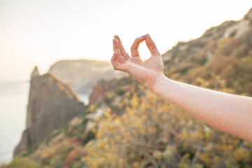 Close-up of female hand, Young woman engaged in yoga in nature with view, makes poses enjoy the meditation, balance and sunrise