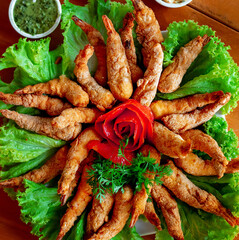 shrimp breaded and fried in oil on a large plate with tomato decoration and green leaves, typical brazilian snack, plate with seafood