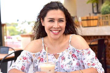 Mujer bonita latina sonriendo sentada en cafetería restaurante