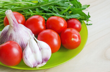 Fresh tomatoes, garlic and arugula on a plate.