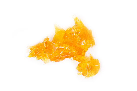 golden drops cannabis wax close up macro on white background.