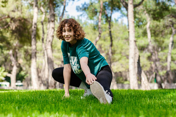 Fototapeta na wymiar Beautiful young redhead woman wearing sportive clothes standing on city park, outdoors stretching leg muscles, doing side lunges in skandasana pose. Healthy lifestyle concept.