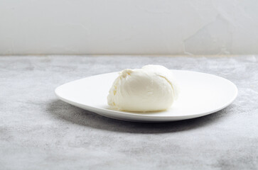 Italian  cheese burrata on white plate on concrete surface.