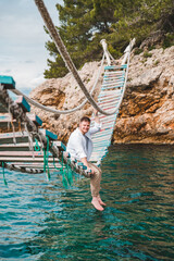 man sitting at suspension bridge enjoying sea view and nature calmness
