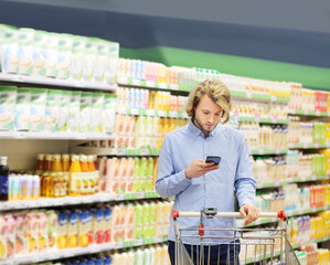 Young man choosing a dairy products at supermarket, reading product information