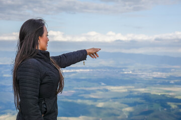 Mulher apontando para uma vista de cima da montanha