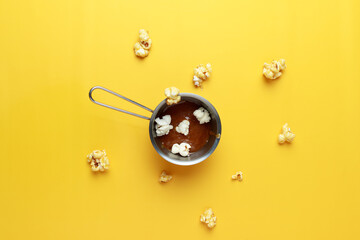 Caramel-sweet popcorn in a metal bowl. Yellow background. Photography for advertising cinemas, cafes, restaurants, coffee houses. Horizontal photo.