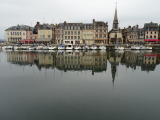 Fototapeta na wymiar mirror reflection of boats and buildings in the harbor of honfleur, normandy, france