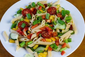 dish of penne pasta salad with tomatoes and cucumbers