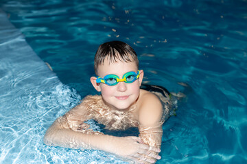 Naklejka premium A smiling boy swims in the pool. Sports and recreation. Leisure activities and lifestyle