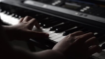 detail shot of a young latin man's hands. brown guy playing synthesizer or electric piano at home, practicing for his exam in classical music class. music concept online

