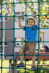 Obraz premium Boy In Adventure Park having fun in high wire park. Male toddler on climbing net.