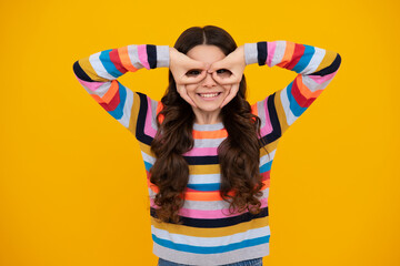 Beautiful teenager child girl look finger specs okey symbol silly shapes figures isolated on yellow background. Funny kids face.