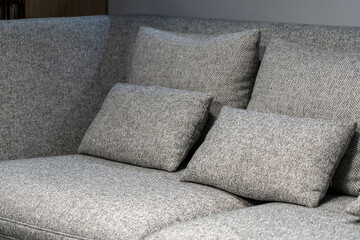 Close up light grey fabric sofa with warm cozy home interior background. Pillows on grey sofa room decoration background