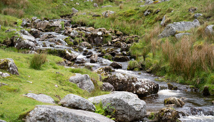 runoff water flows over rocks and boulders in a mountain pass in the Brecon Beacons, South Wales.