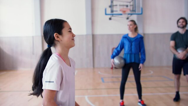 Group of little kids doing physical exercises with fitballs in gym at school.
