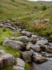 Naklejka na ściany i meble runoff water flows over rocks and boulders in a mountain pass in the Brecon Beacons, South Wales.
