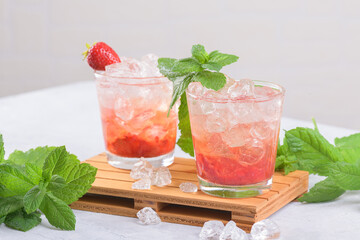 Cold summer strawberry iced cocktail mojito, margarita, daiquiri in two glasses with mint leaves on light background