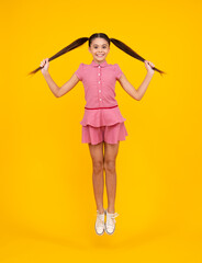 Happy teenager, positive and smiling emotions of teen girl. Excited teenager. Full length funny teenager kid jump enjoy rejoice win isolated on yellow background. Small child girl in dress jumping.