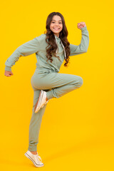 Fototapeta na wymiar Cute teenager girl in a purple casual sports suit. Child in a stylish sports suit on yellow background isolated.