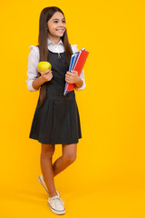 Full length of schoolchild, teenage student girl with school bag backpack hold aplle on yellow isolated studio background. Children school and education concept.